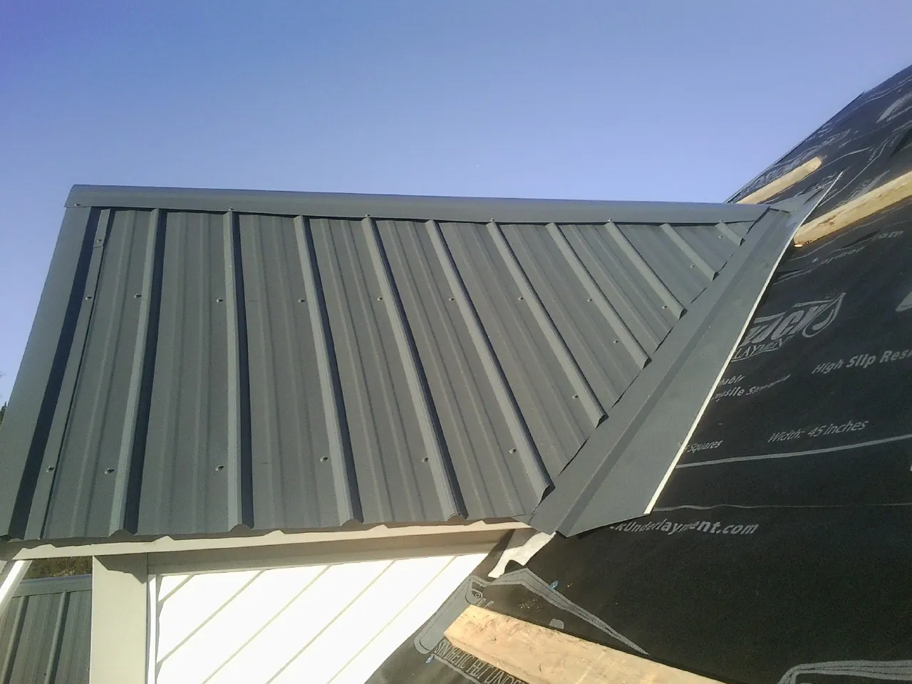 Gray metal roof panels going on over a garage gable in Crest Hill