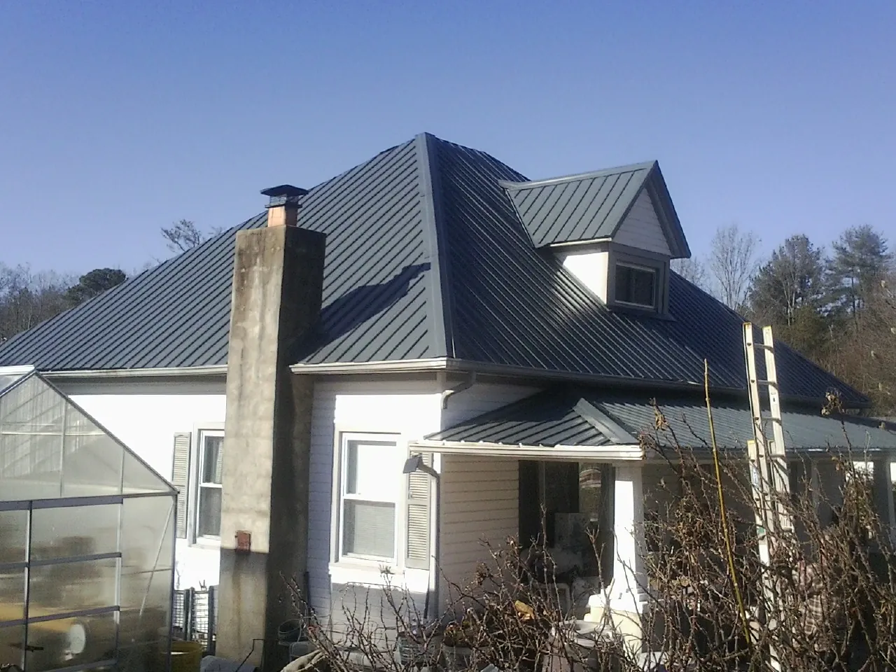 Dark blue standing seam metal roof on a white farmhouse with dormer — Slate & Tile Roof Repair by Roofing Brothers in Crest Hill