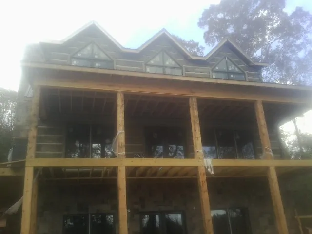 Dormers and porch framing on a large log home under construction — Roof Coating work by our crew in Crest Hill