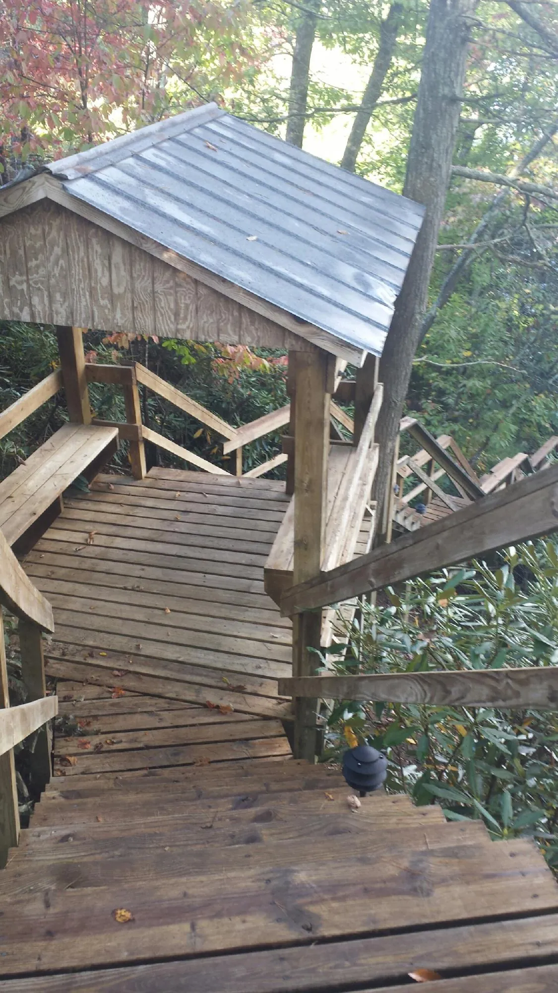 Metal roofed shelter over wooden steps on a wooded walkway — Skylight Repair & Installation work by our crew in Crest Hill
