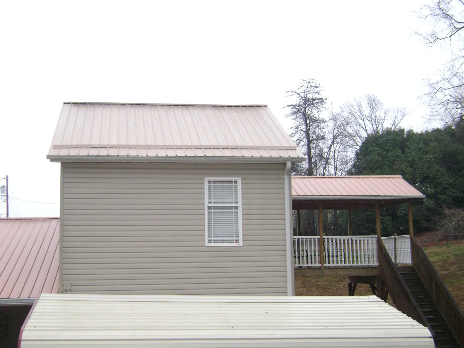 Tan metal roofs on a two story addition and attached porch, from a Roof Replacement job in Crest Hill