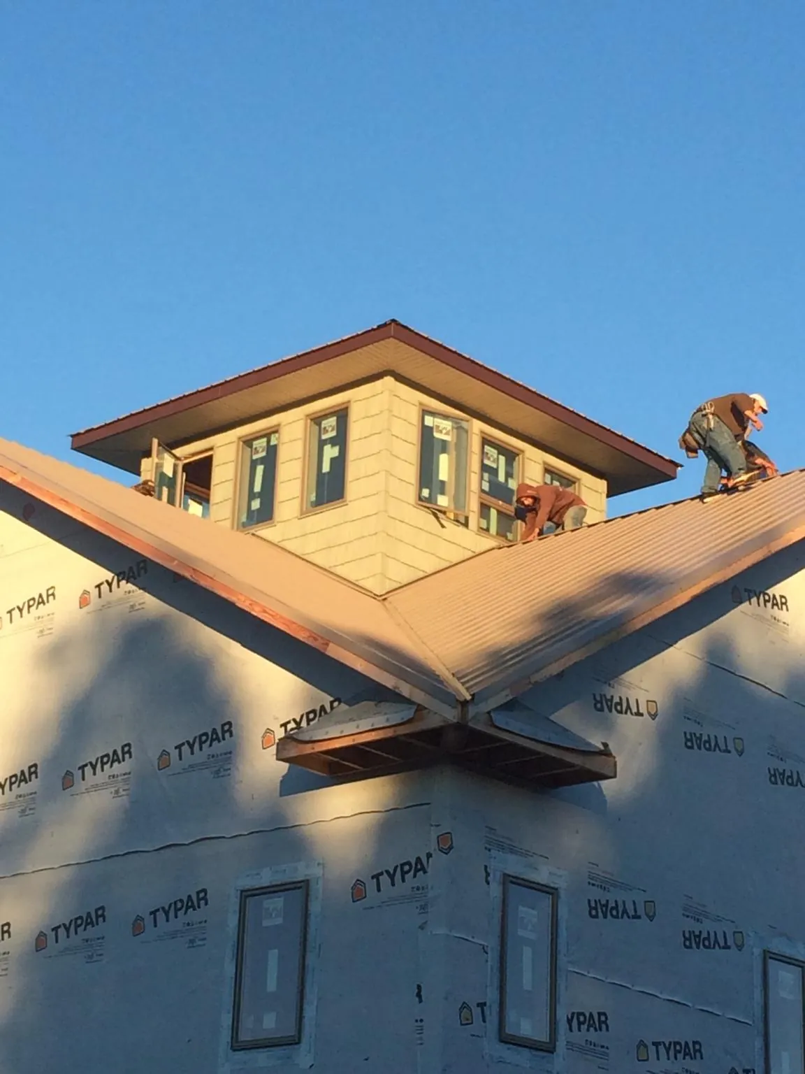 Roofers working around a rooftop cupola on a new metal roof at sunset — Roof Waterproofing in Crest Hill by Roofing Brothers